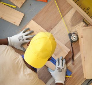 A Man Measuring a Wooden Board